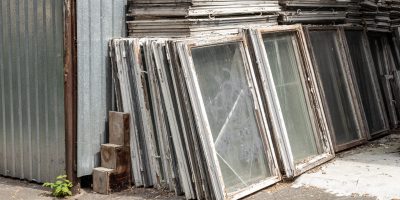Heap of old wooden window frames with glass outdoors. Broken materials after window energy saving technology upgrade.